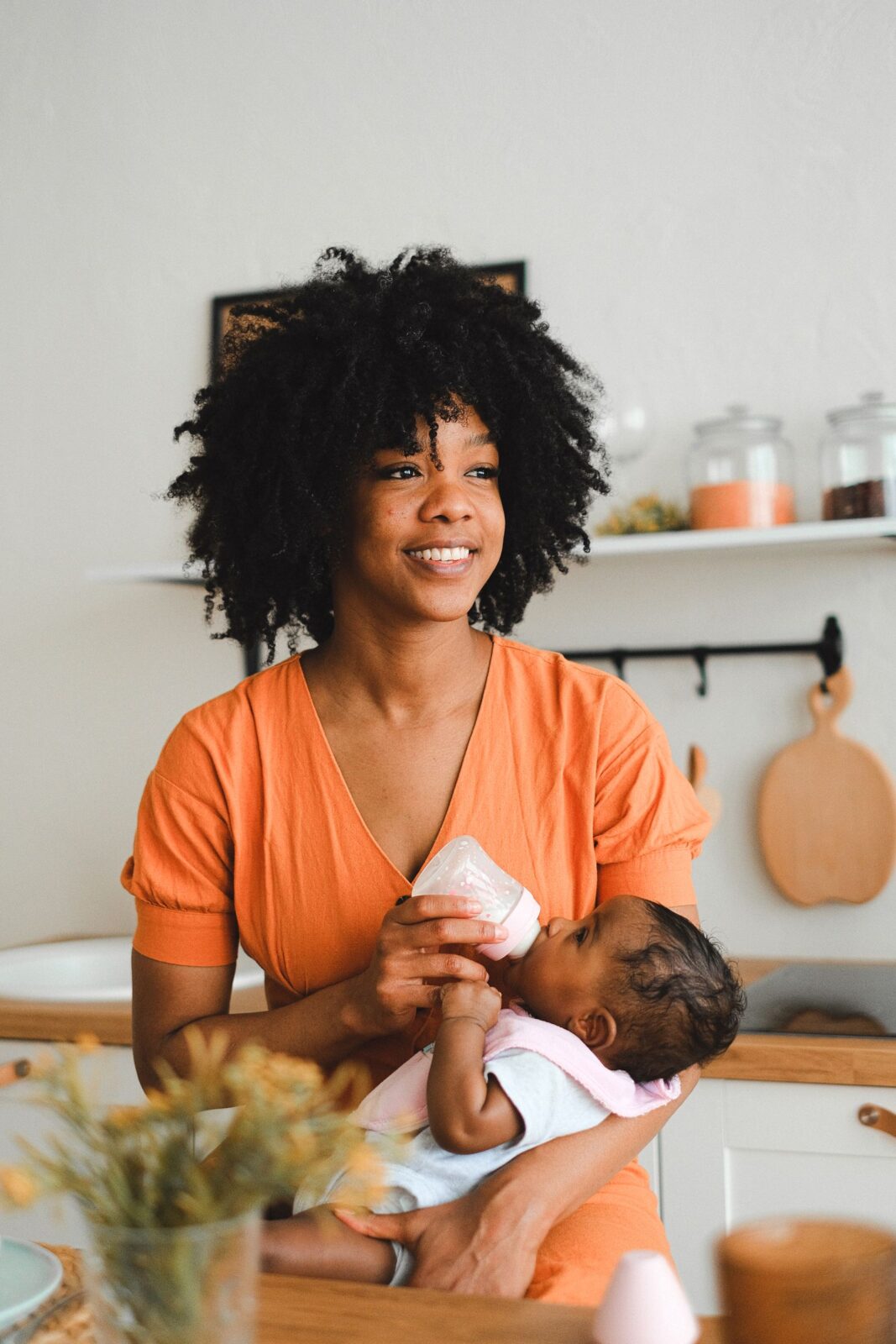 A parent feeding a baby a bottle of milk at home