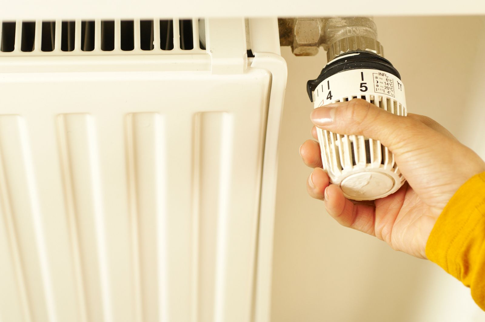 A hand adjusting a home heating control