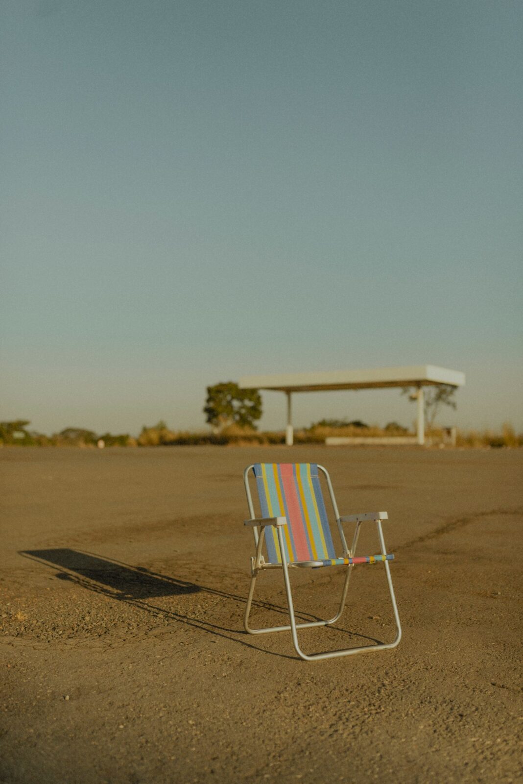 A low folding beach chair on golden sand facing the ocean