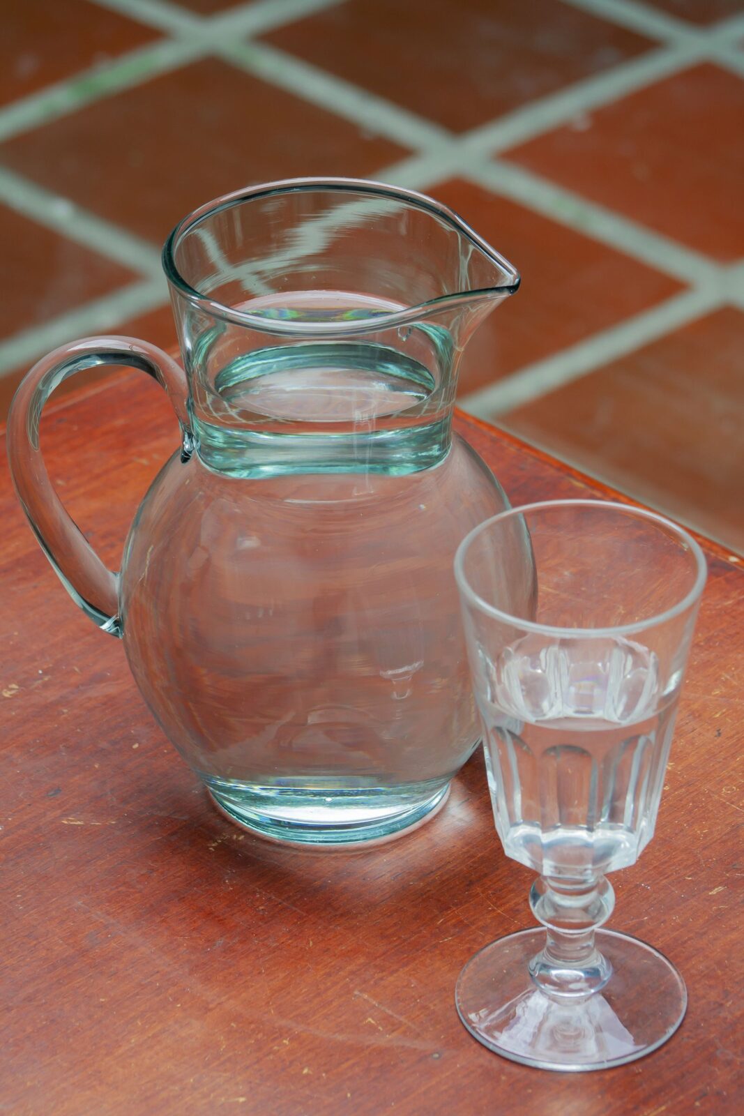 A glass of fresh filtered water beside a pitcher