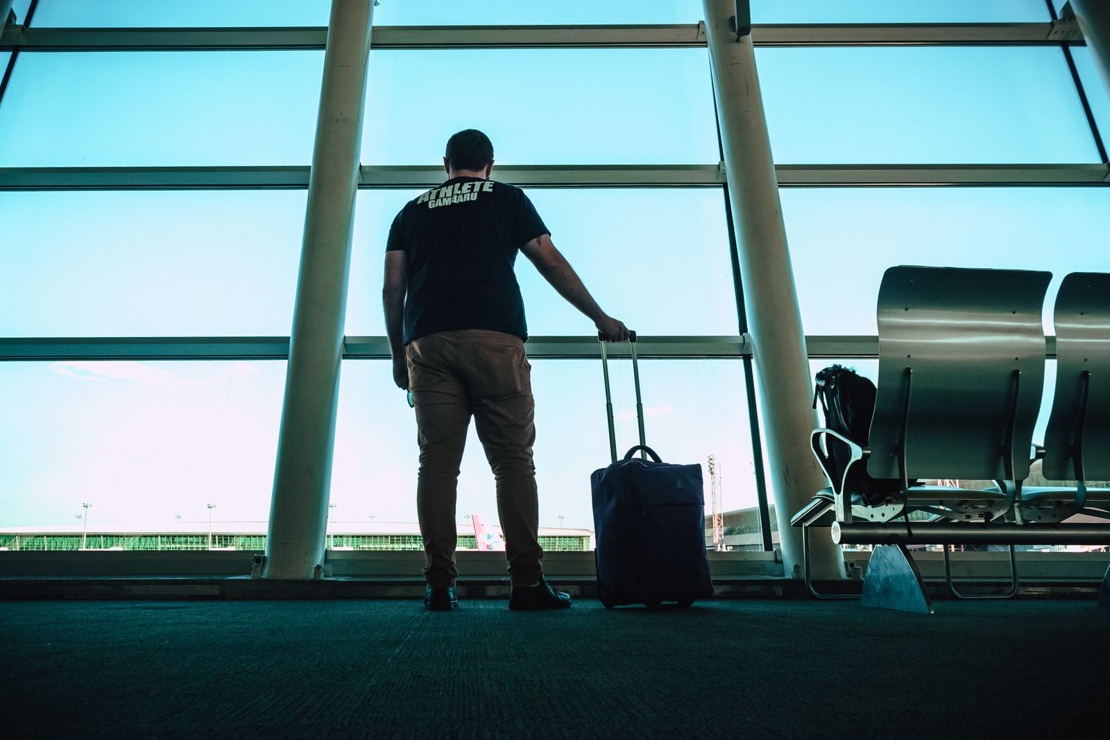A traveler holding a rolling luggage bag