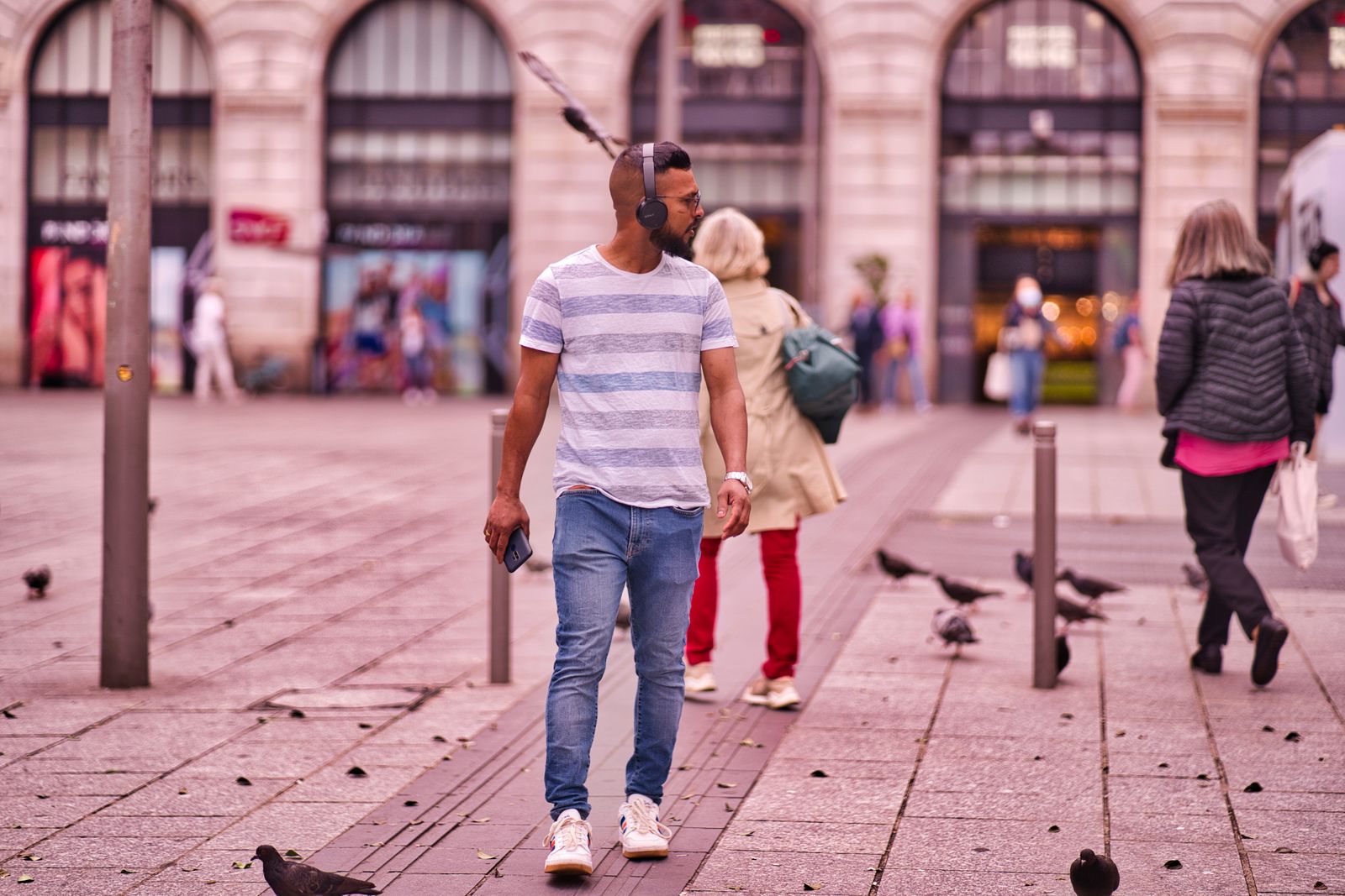 A man wearing over-ear headphones walking through a plaza