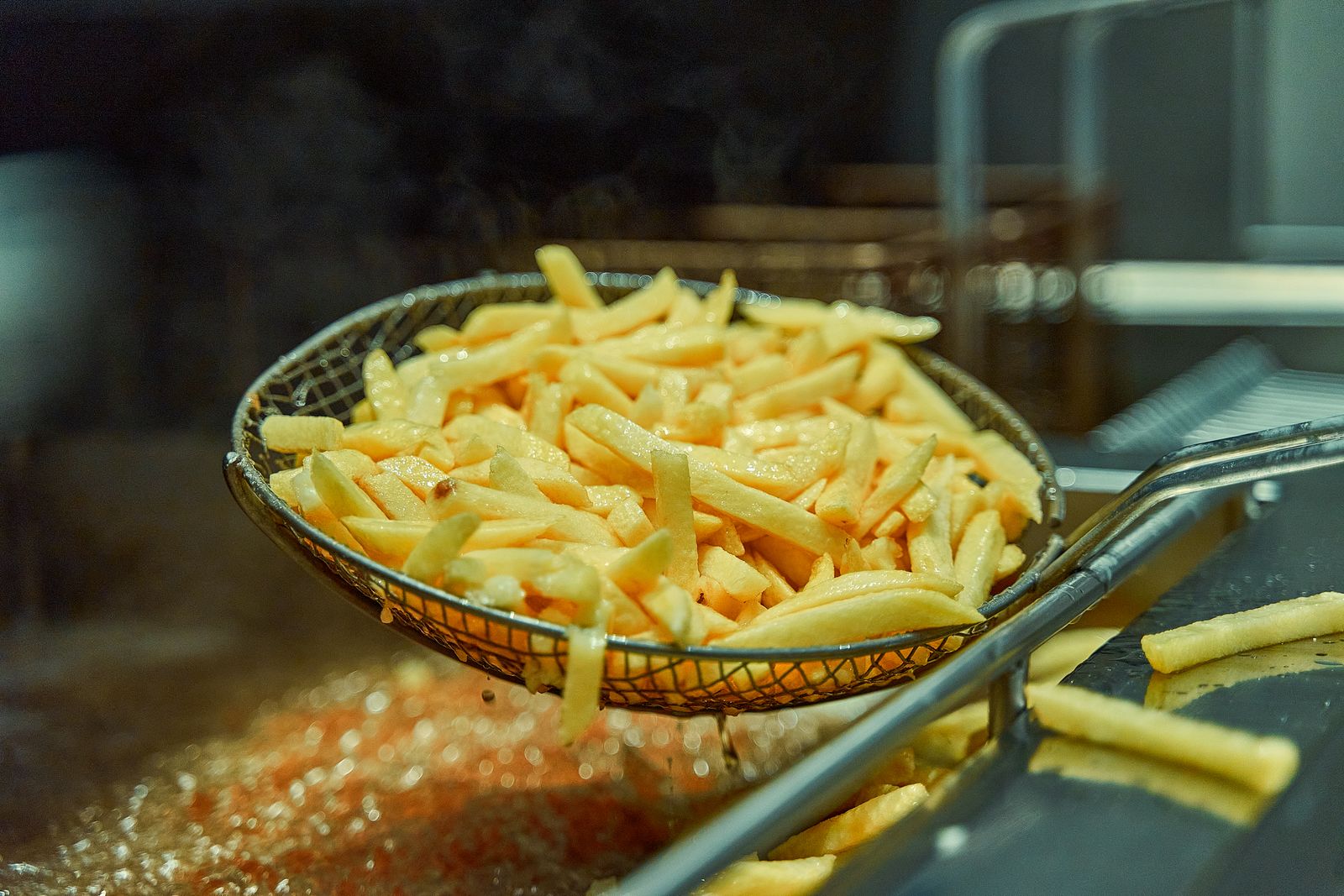 Basket air fryer filled with golden crispy french fries on a kitchen counter