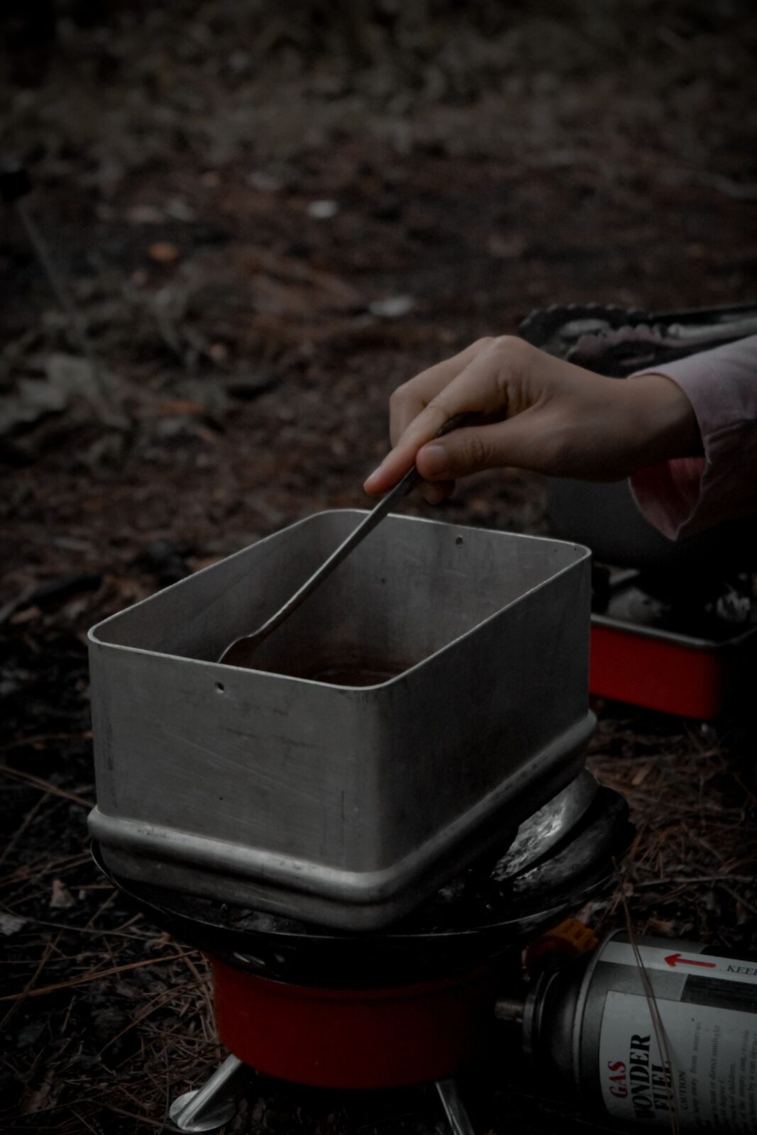 A backpacking canister stove burning under a small pot