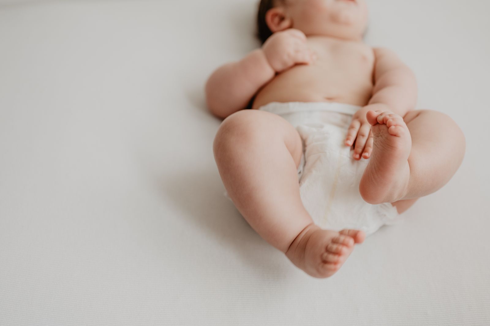 A baby crawling in a plain diaper with a snug fit