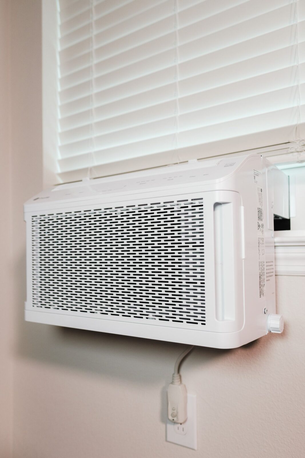 Modern window air conditioner installed in a bright bedroom window