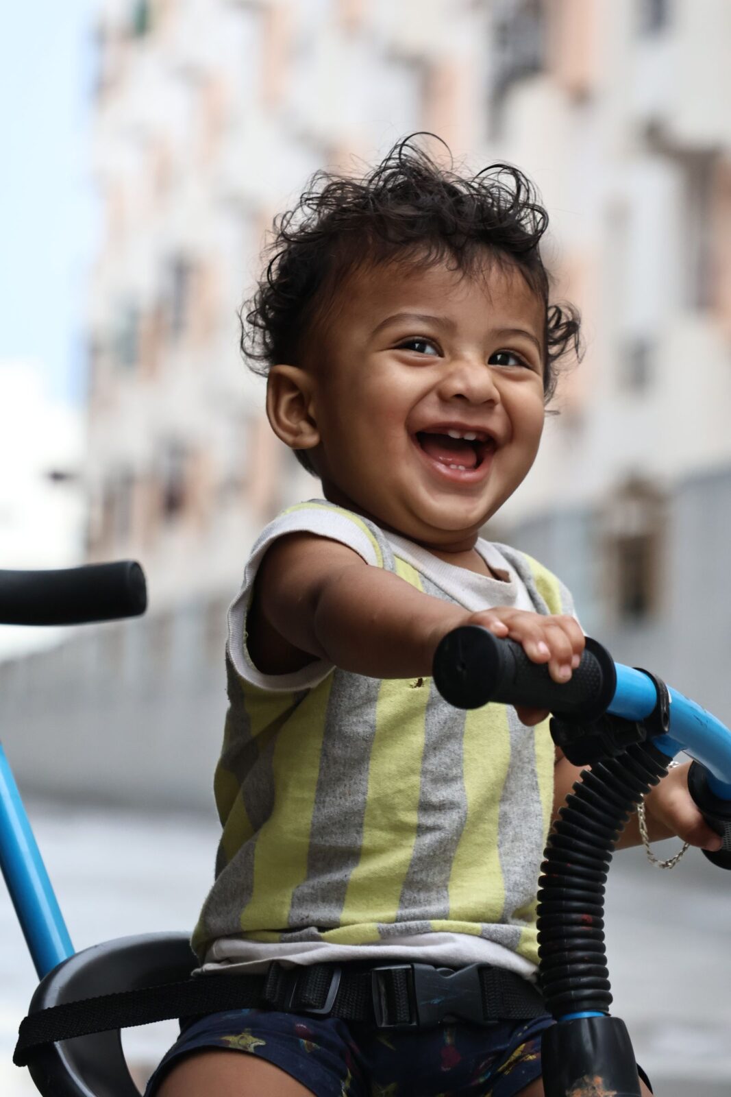 Toddler in a helmet gliding on a balance bike along a sunny sidewalk