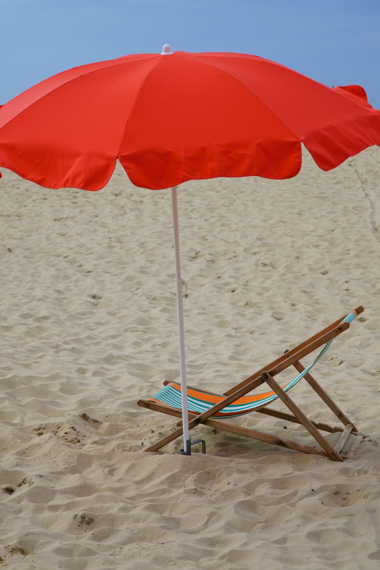 Beach umbrella and deckchair providing shade on a sandy beach