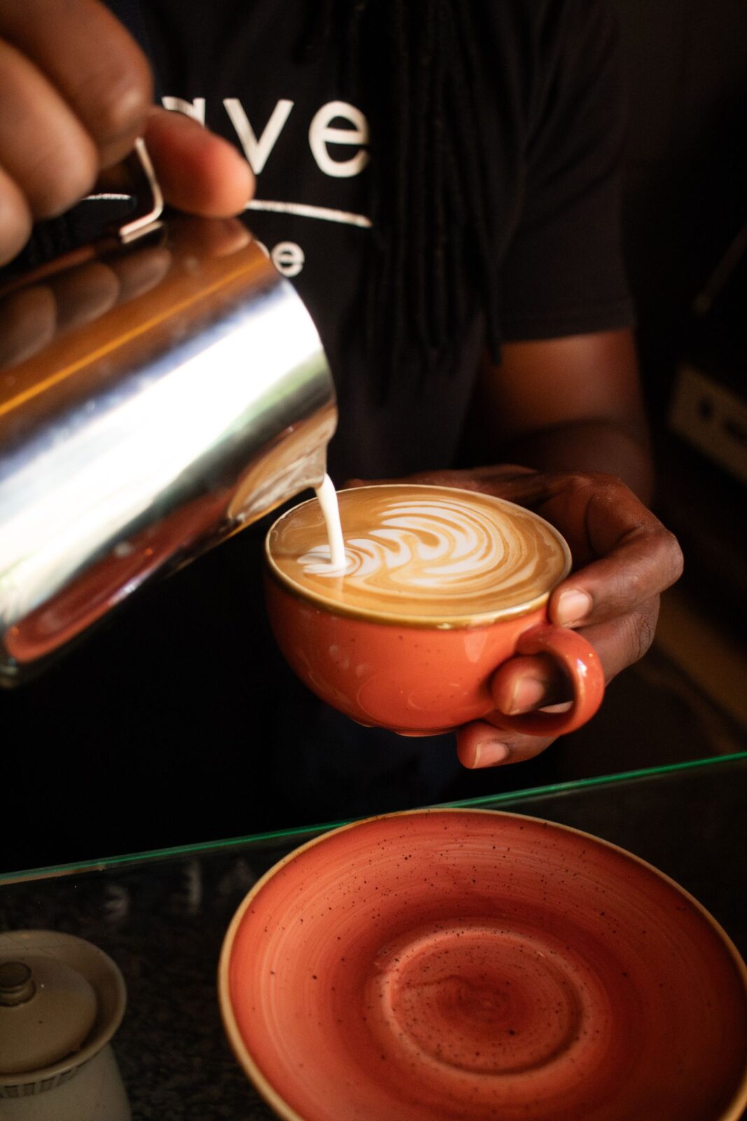 Close-up of frothed milk being poured into a cup of coffee