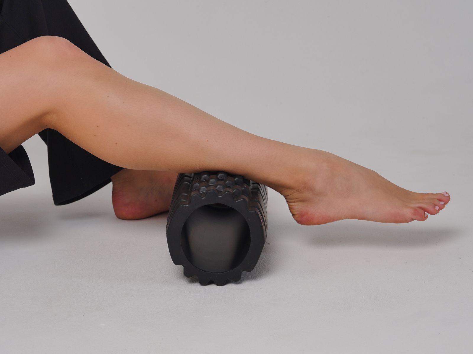 Person foam rolling a leg on a yoga mat