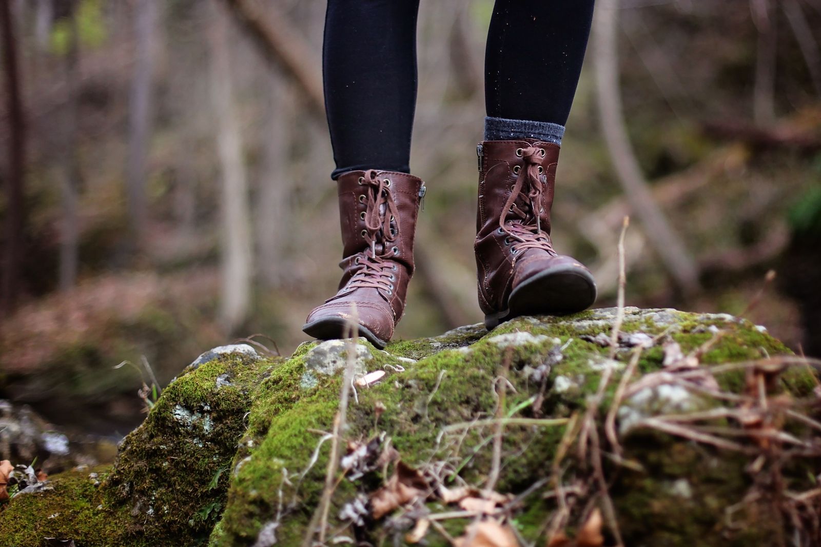 Close-up of a hiker's boots and legs standing on a forest trail