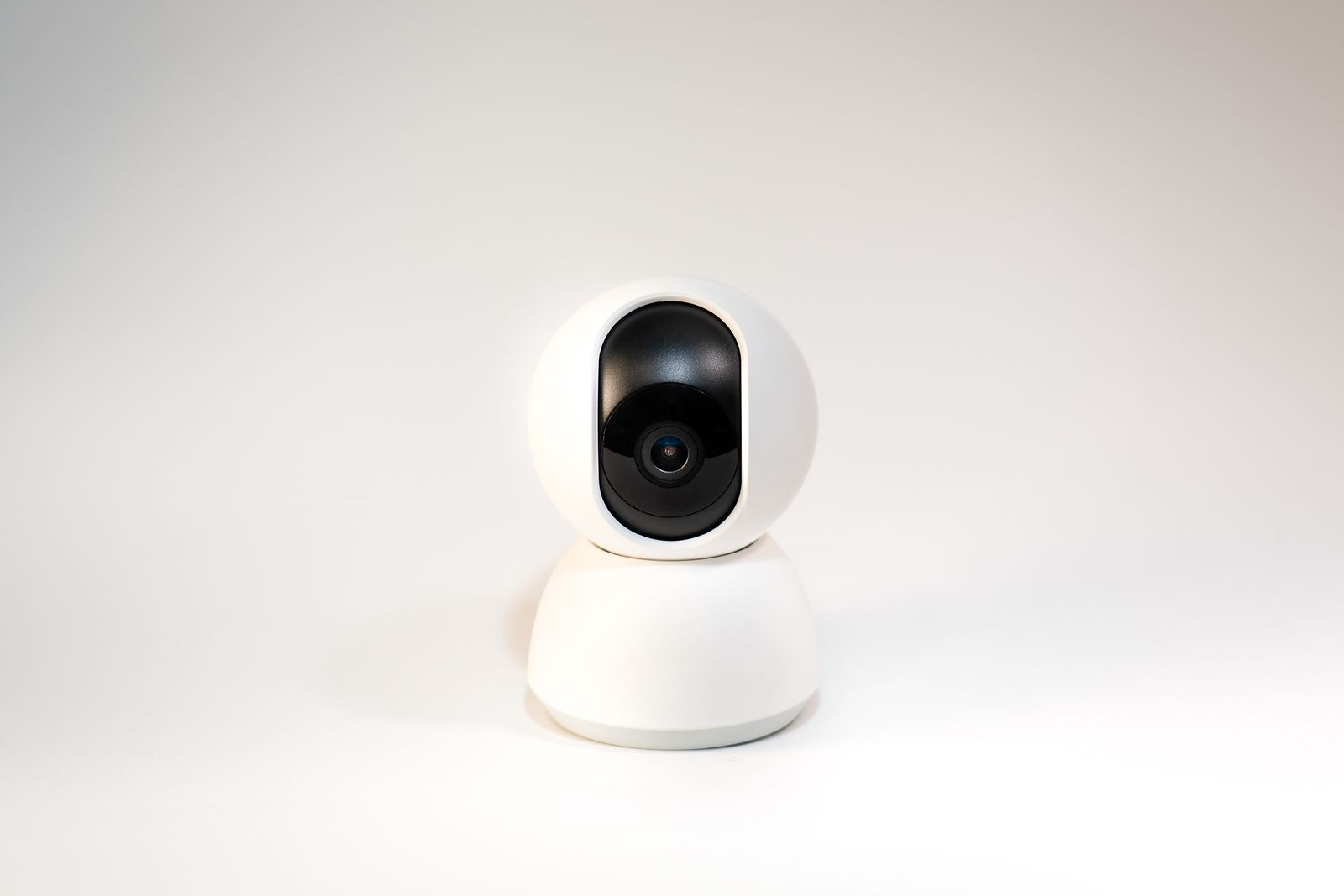 A small home wifi camera on a shelf watching a dog on the couch