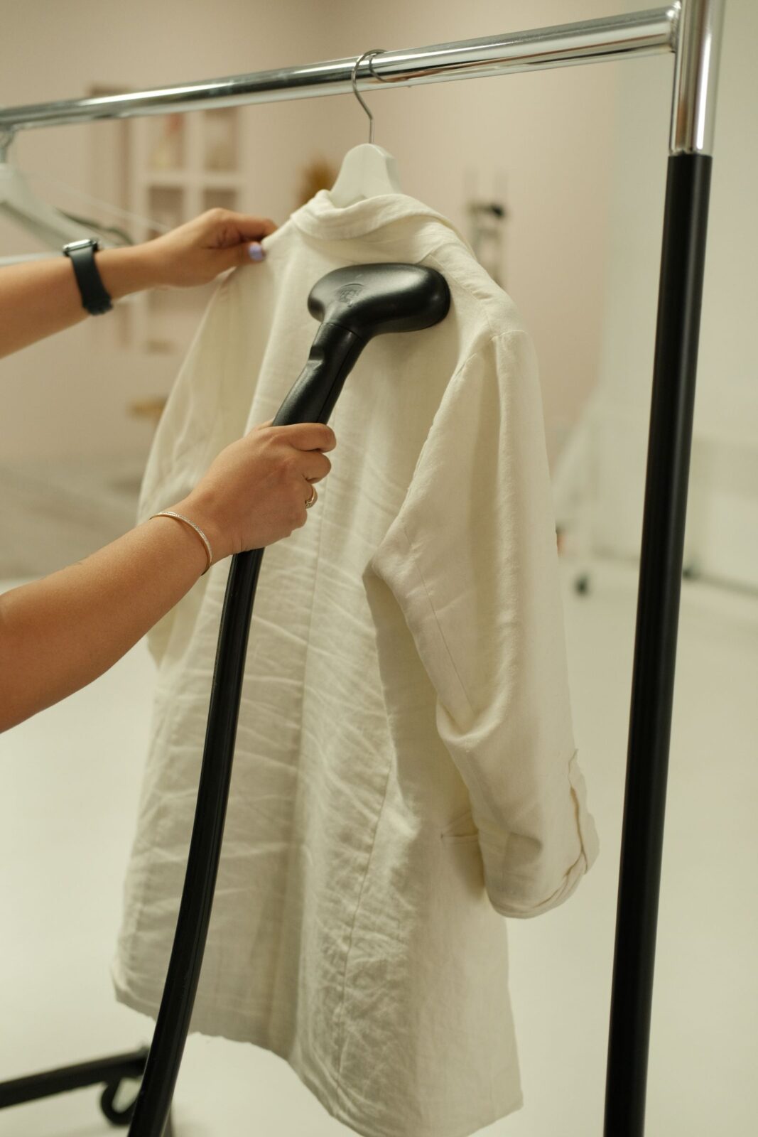Person using a handheld garment steamer to smooth wrinkles from a white shirt