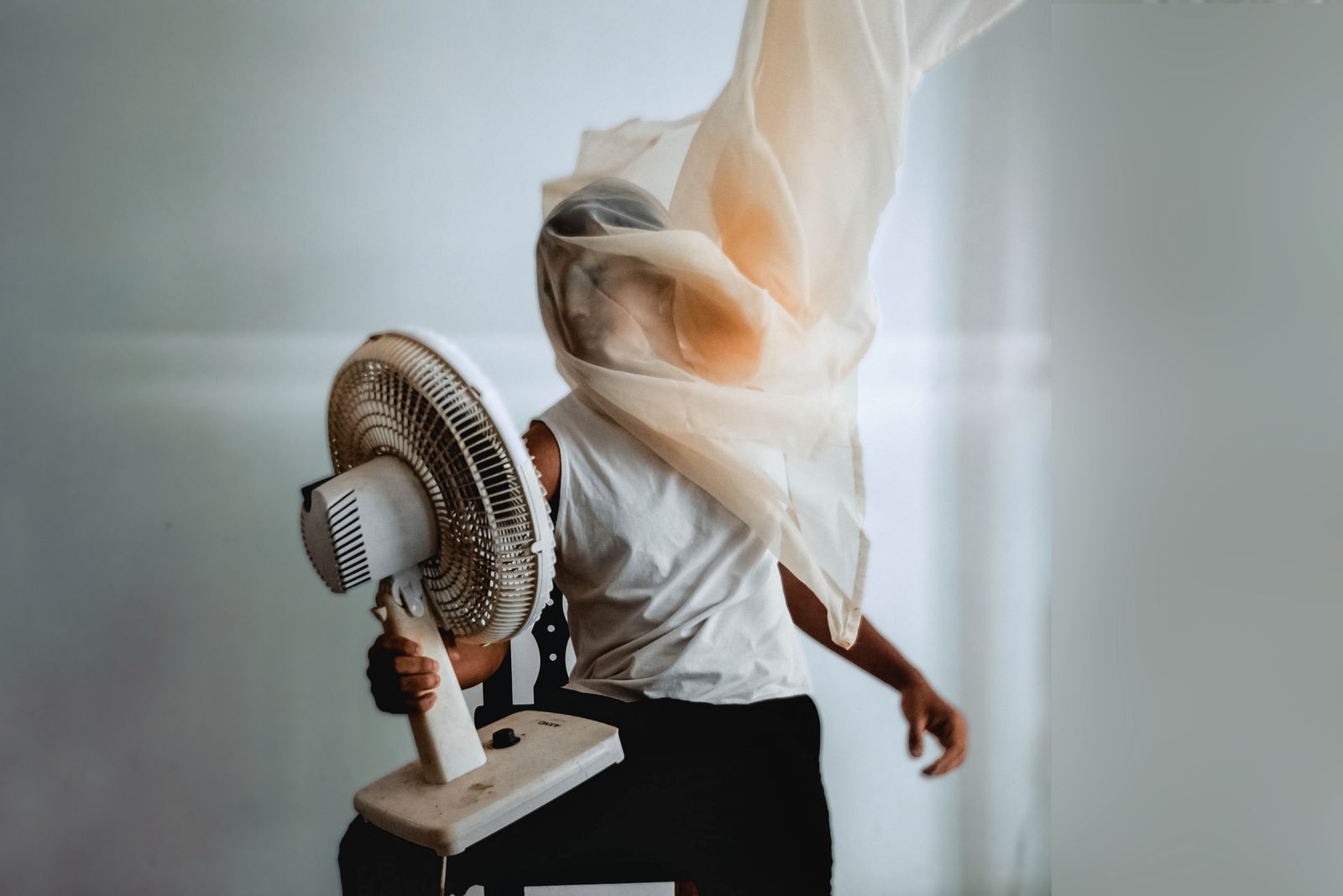 Slim tower fan standing beside a bed in a modern bedroom
