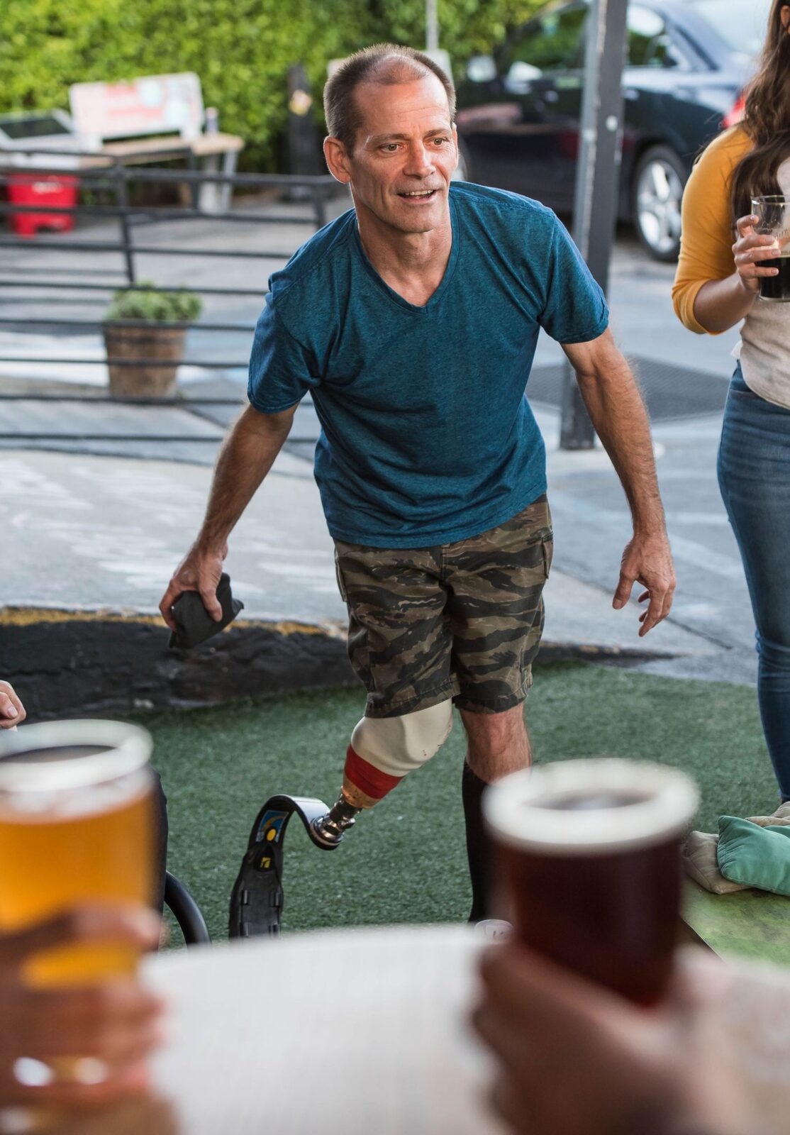 Friends playing cornhole in a sunny backyard, tossing a bean bag toward a wooden board