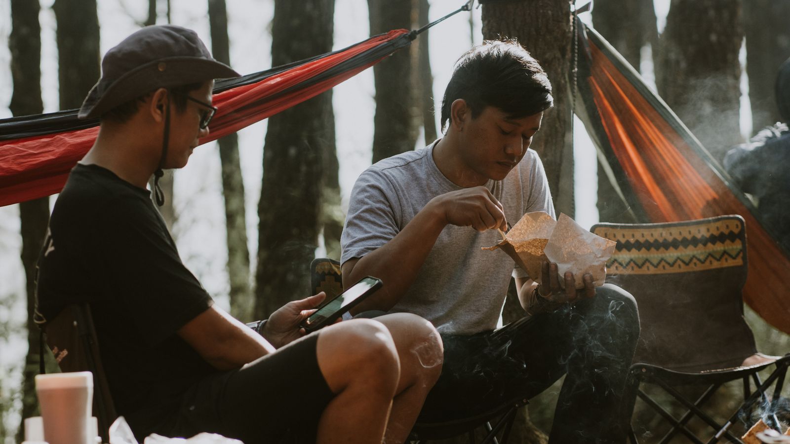 Two friends relaxing in hammocks at a forest camp