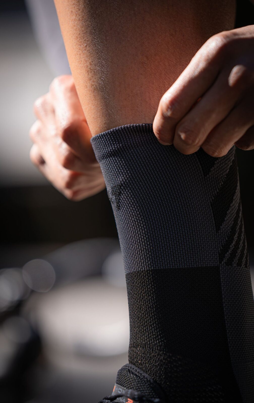 Close-up of a person adjusting a gray athletic compression sock