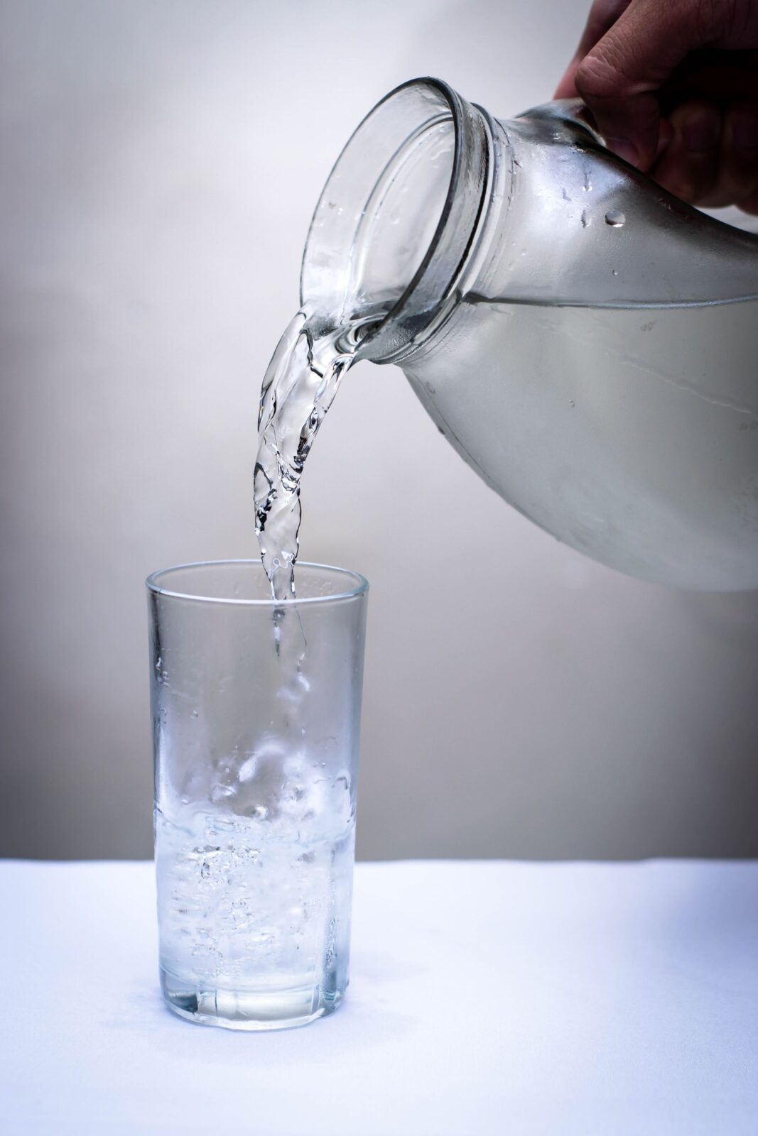 A water filter pitcher pouring filtered water into a glass