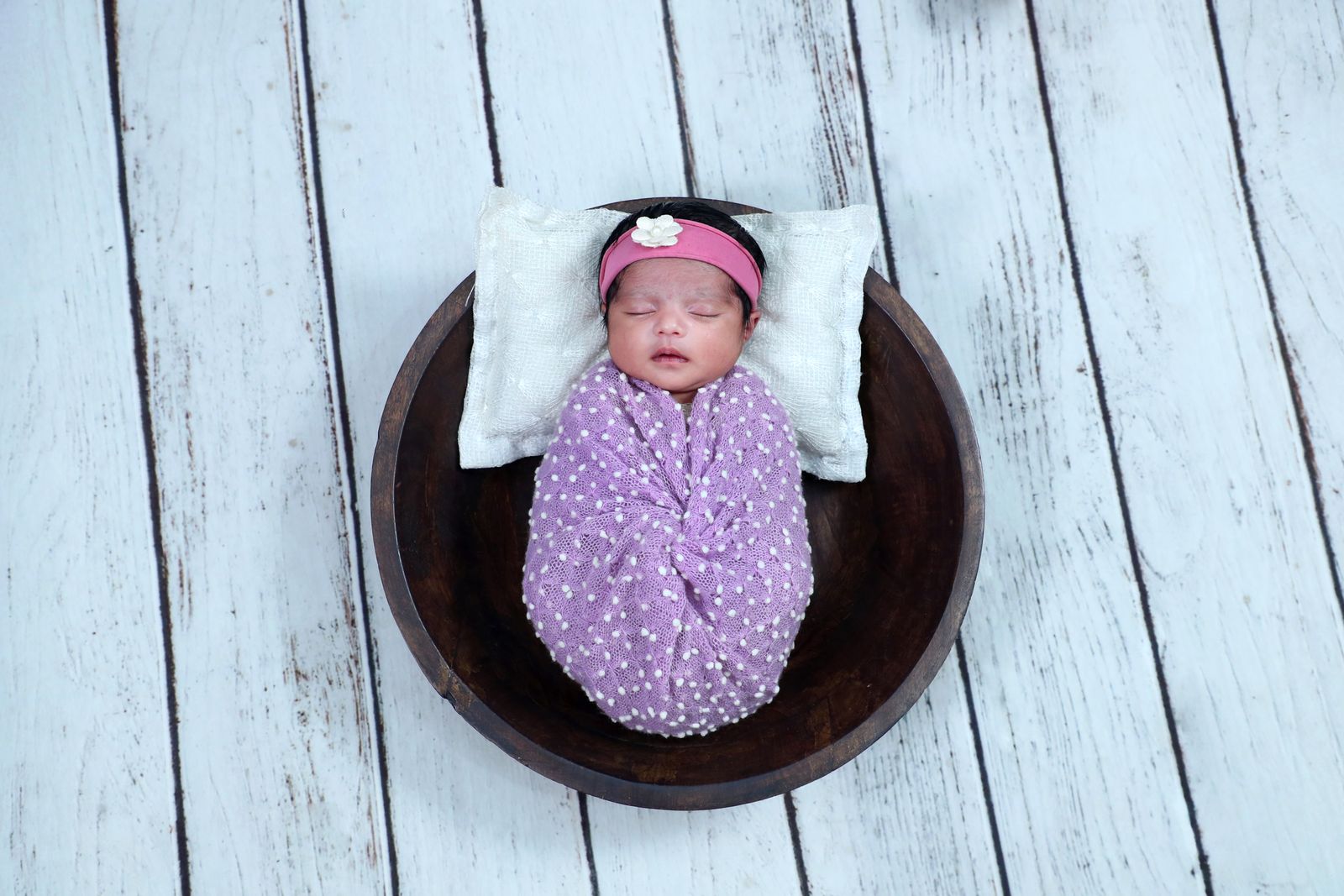 A soft contoured infant lounger cushion on a rug