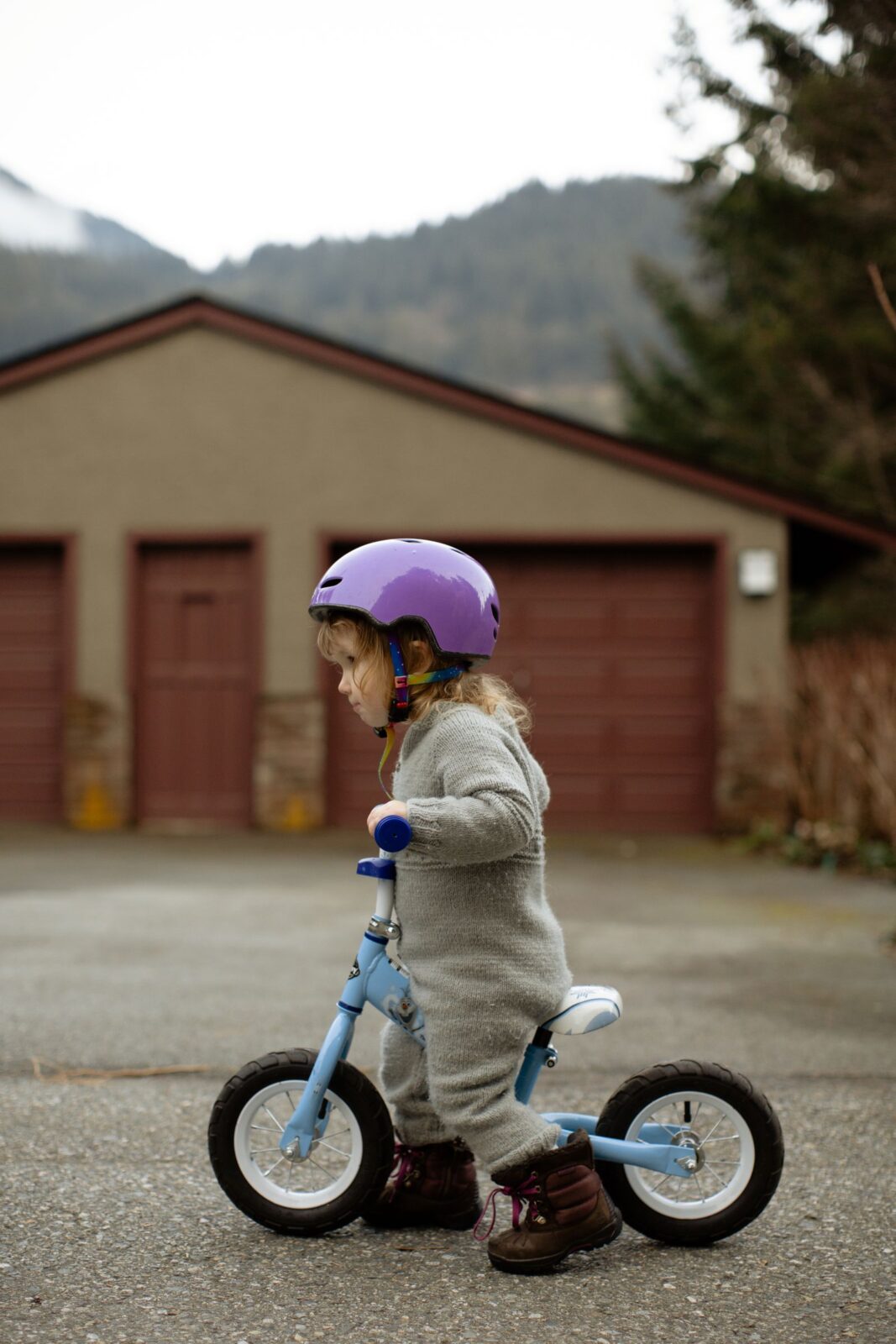 Young child riding a balance bike outdoors on a quiet street