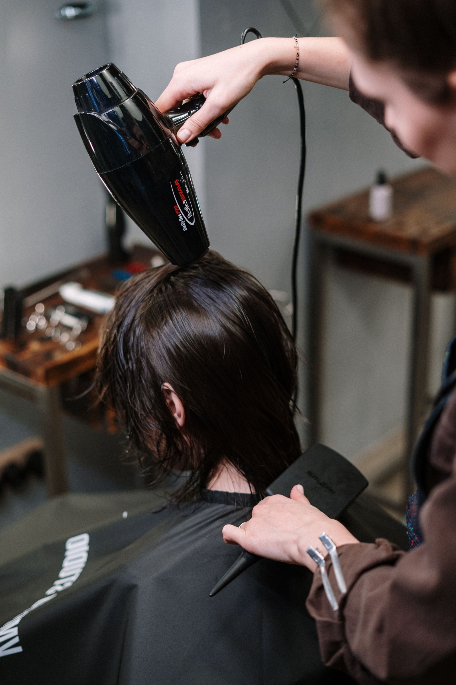 Stylist blow-drying a woman's hair with a round brush in a salon