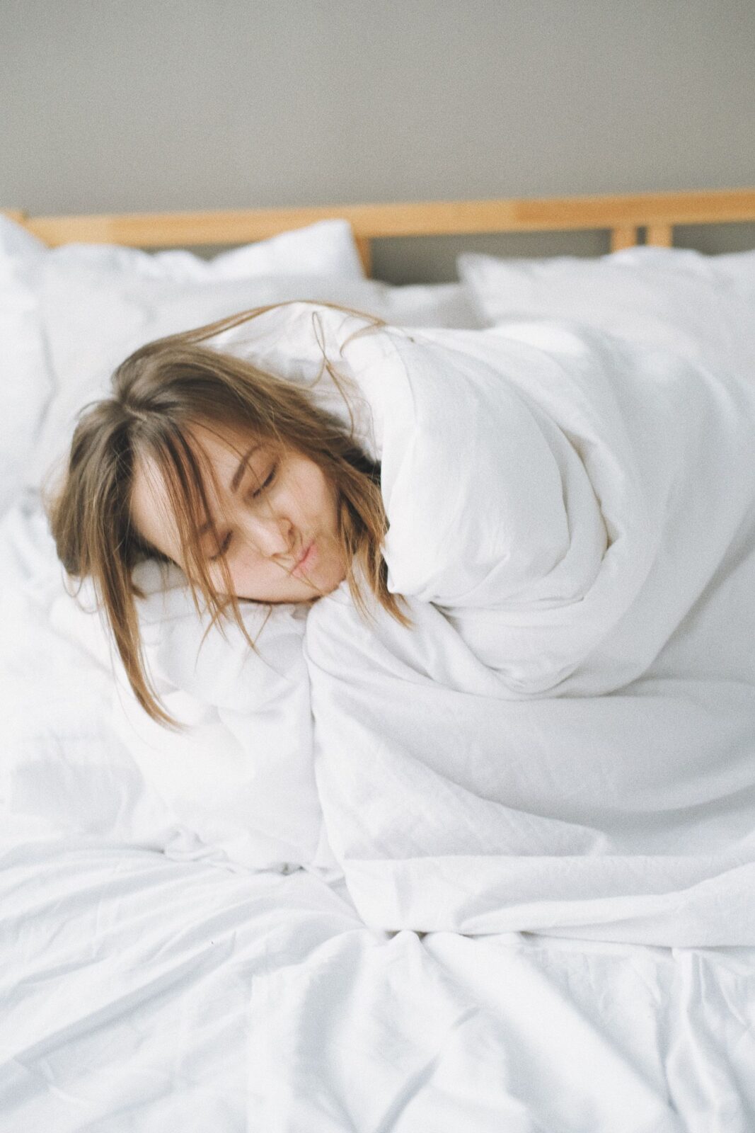 Person resting comfortably under a blanket in bed