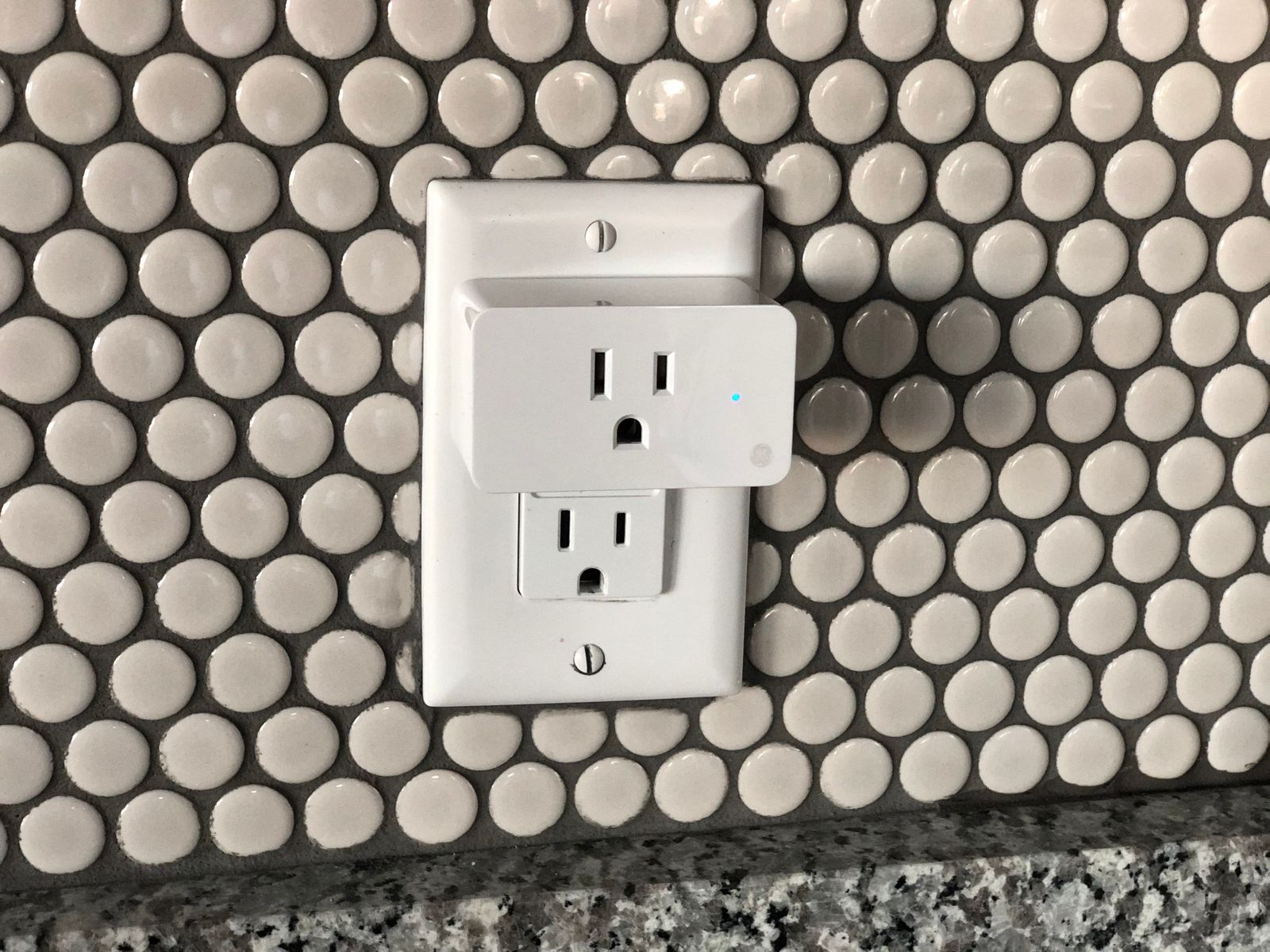 Close-up of a smart plug inserted into a wall outlet controlling a connected lamp cord