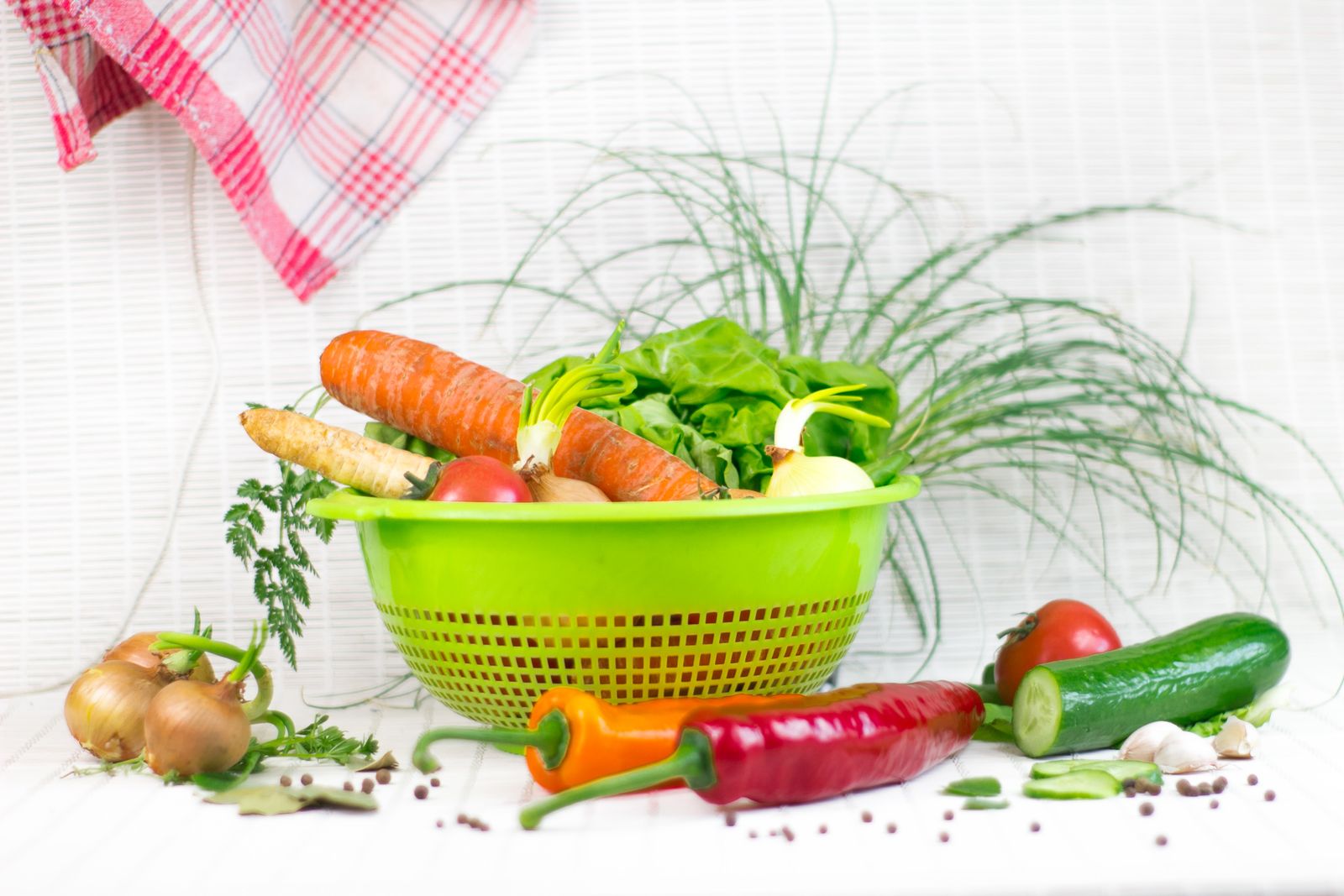 Fresh vegetables and herbs sitting in a plastic colander basket, similar to a salad spinner basket, ready for washing