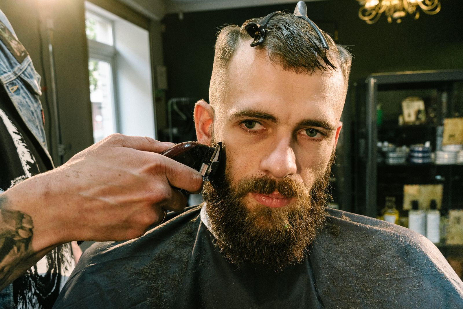 A barber trimming a client's beard with professional tools