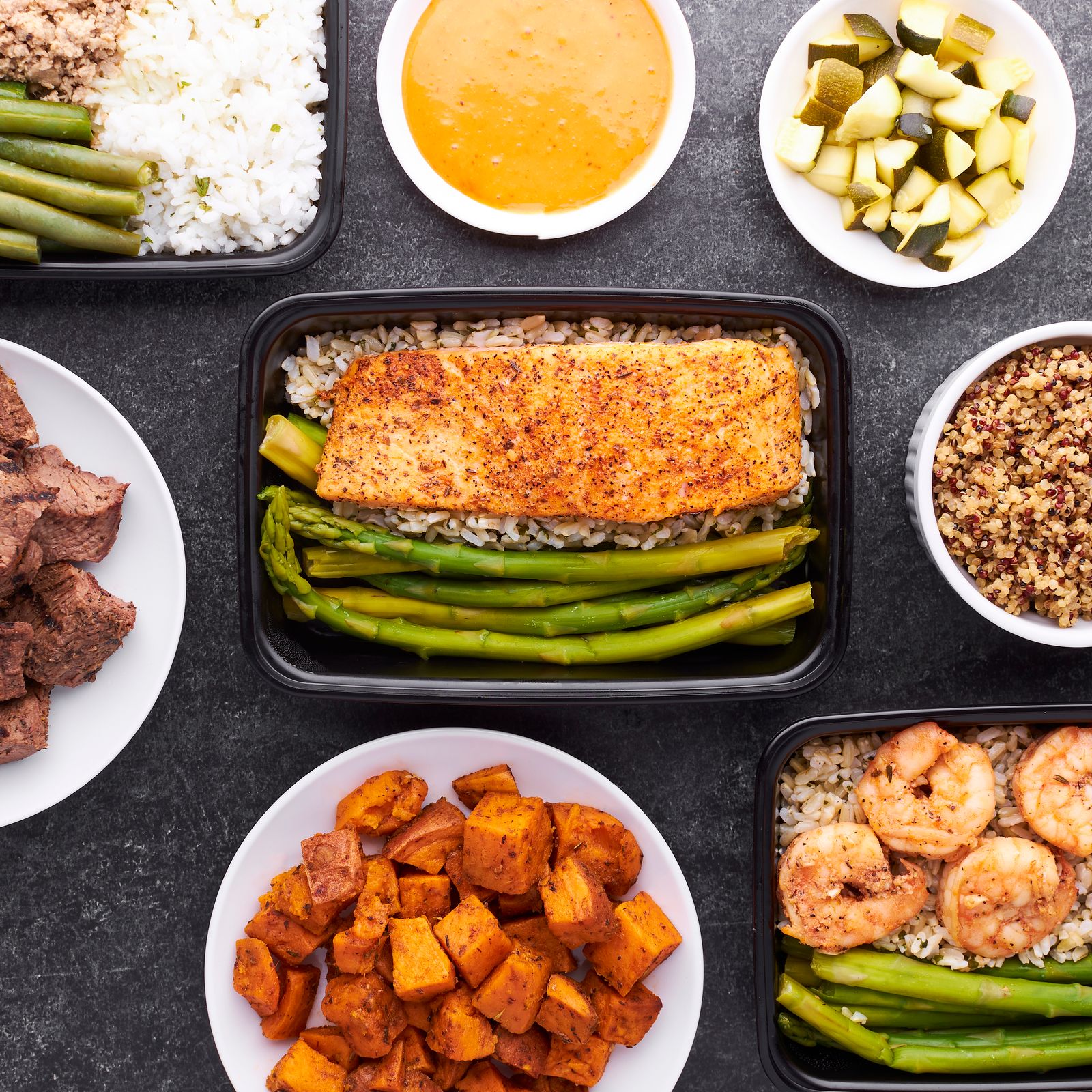 Flat lay of healthy prepared meal delivery containers with salmon, vegetables, and grains