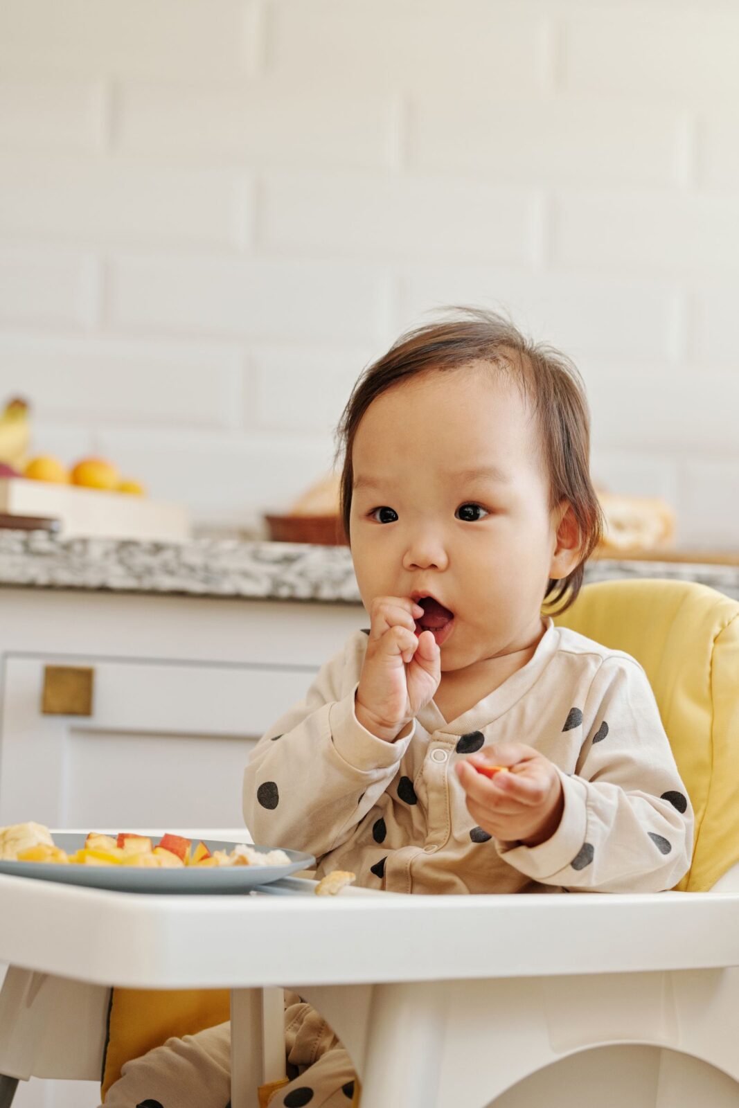 A toddler sitting in a high chair eating a meal
