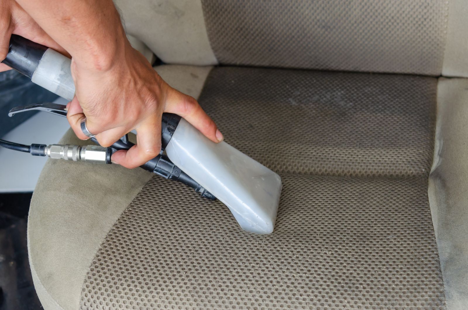 A person deep cleaning an upholstered car seat