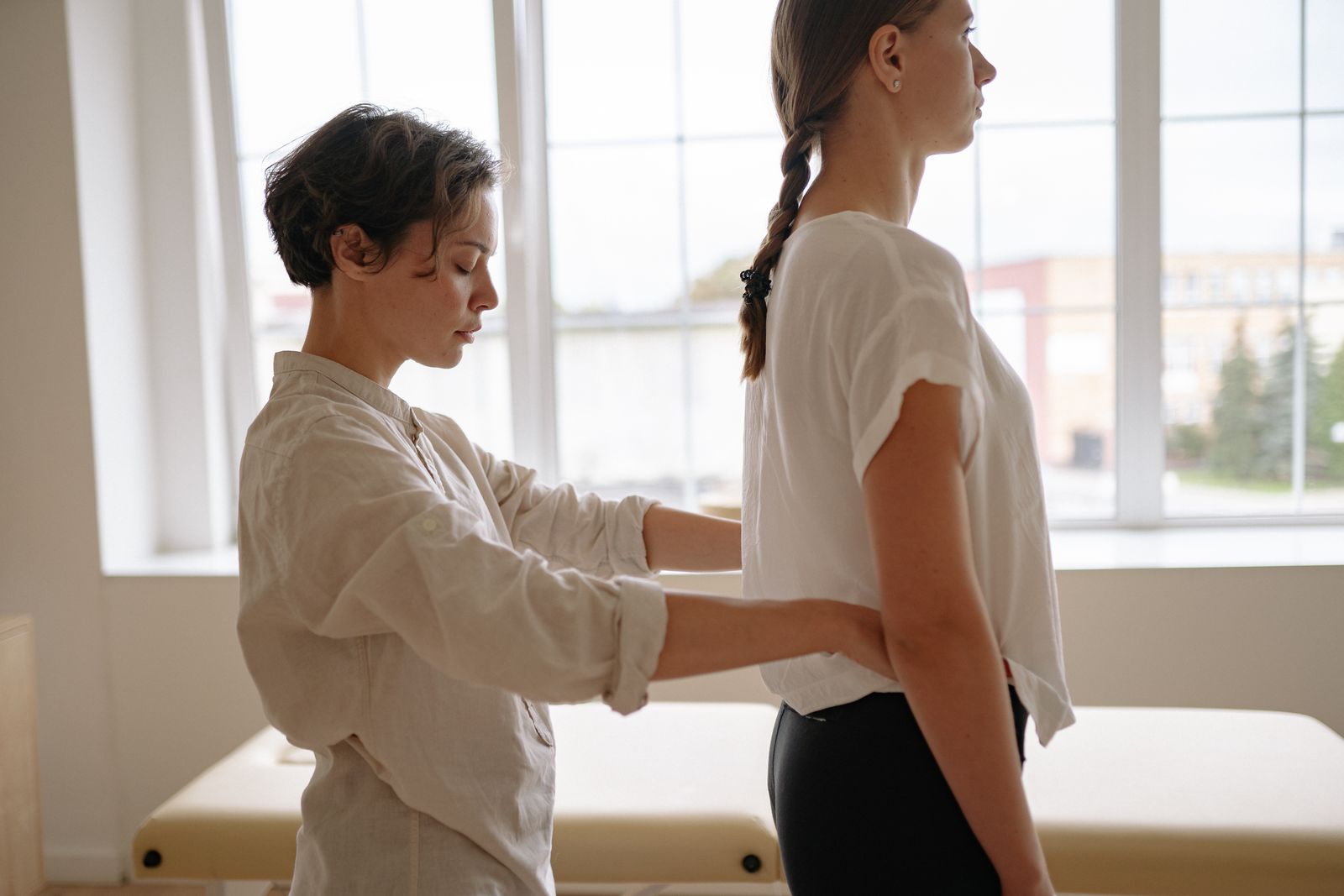 Physical therapist adjusting a standing patient's posture during a clinical assessment