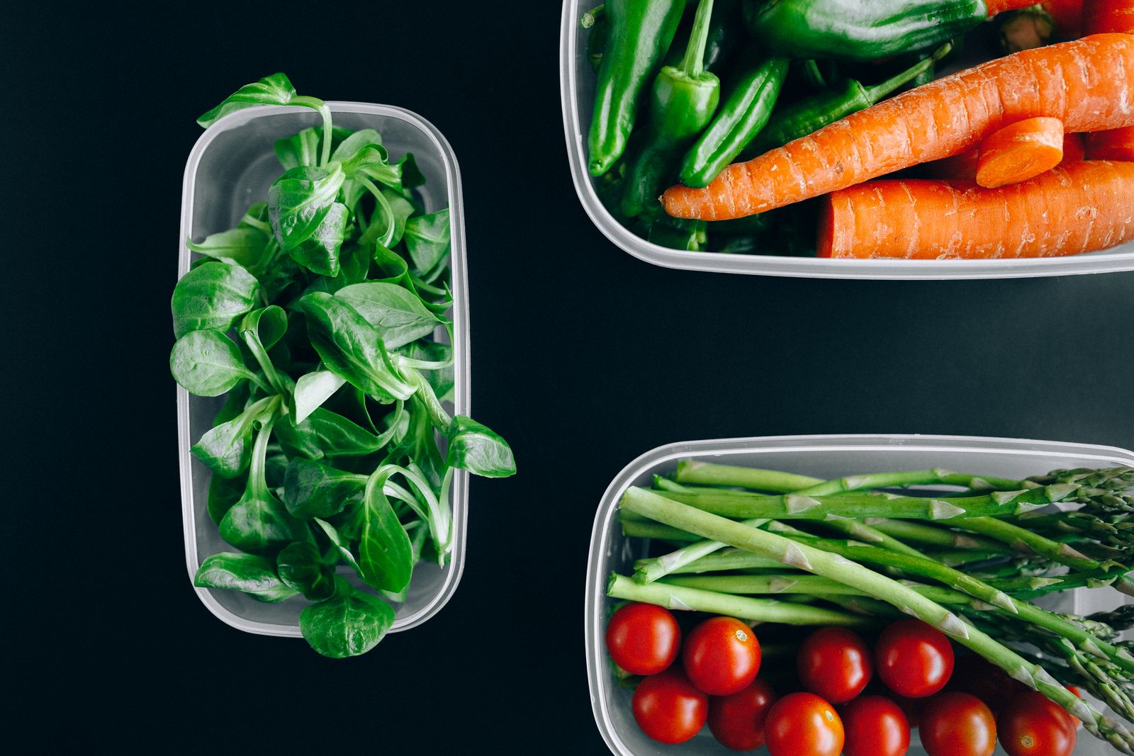 Fresh vegetables portioned into meal prep containers on a kitchen counter