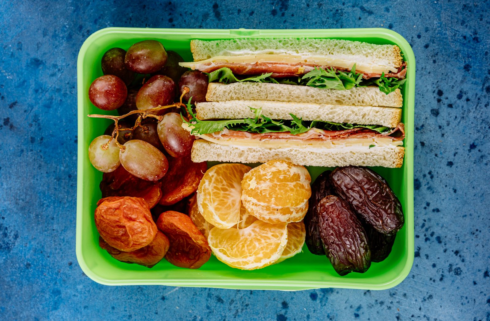 A packed lunch box with a sandwich and fresh fruit