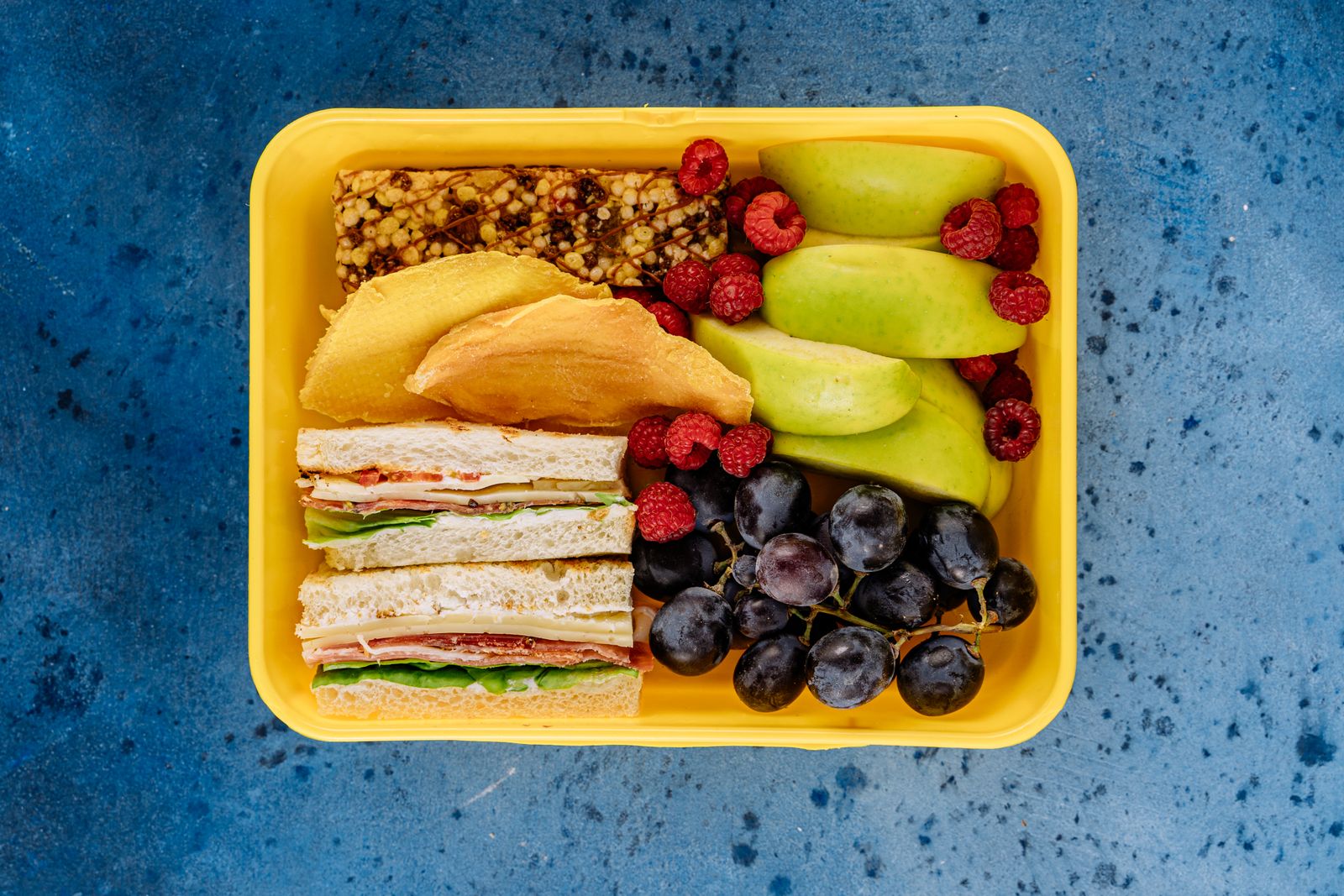 Packed lunch box with fruit and sandwiches in separate compartments