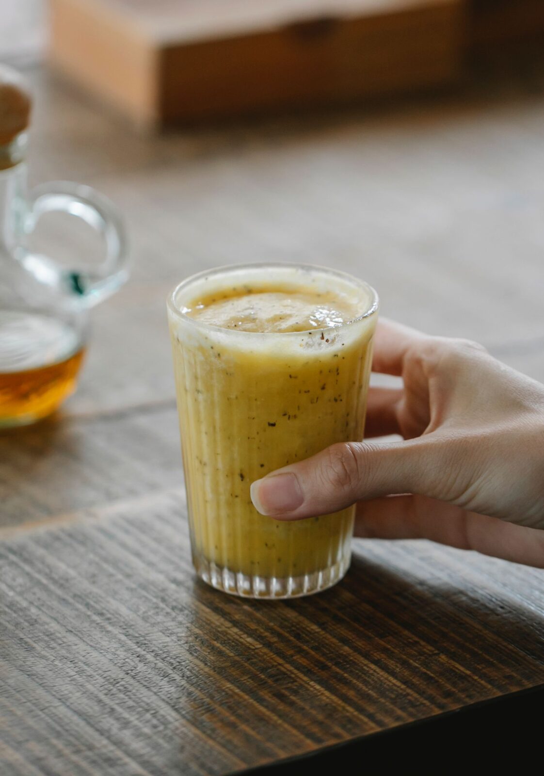 Person holding a glass of a thick protein shake or smoothie