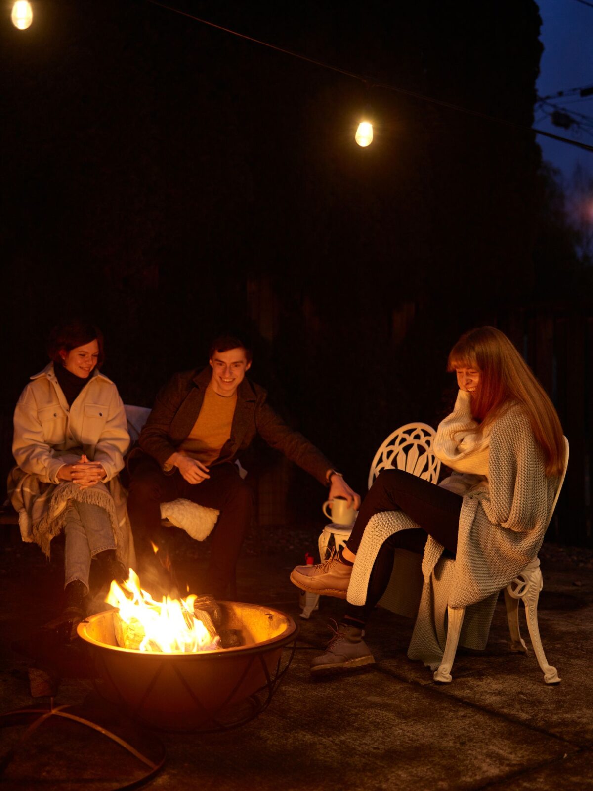 Friends gathered around a backyard fire pit at dusk
