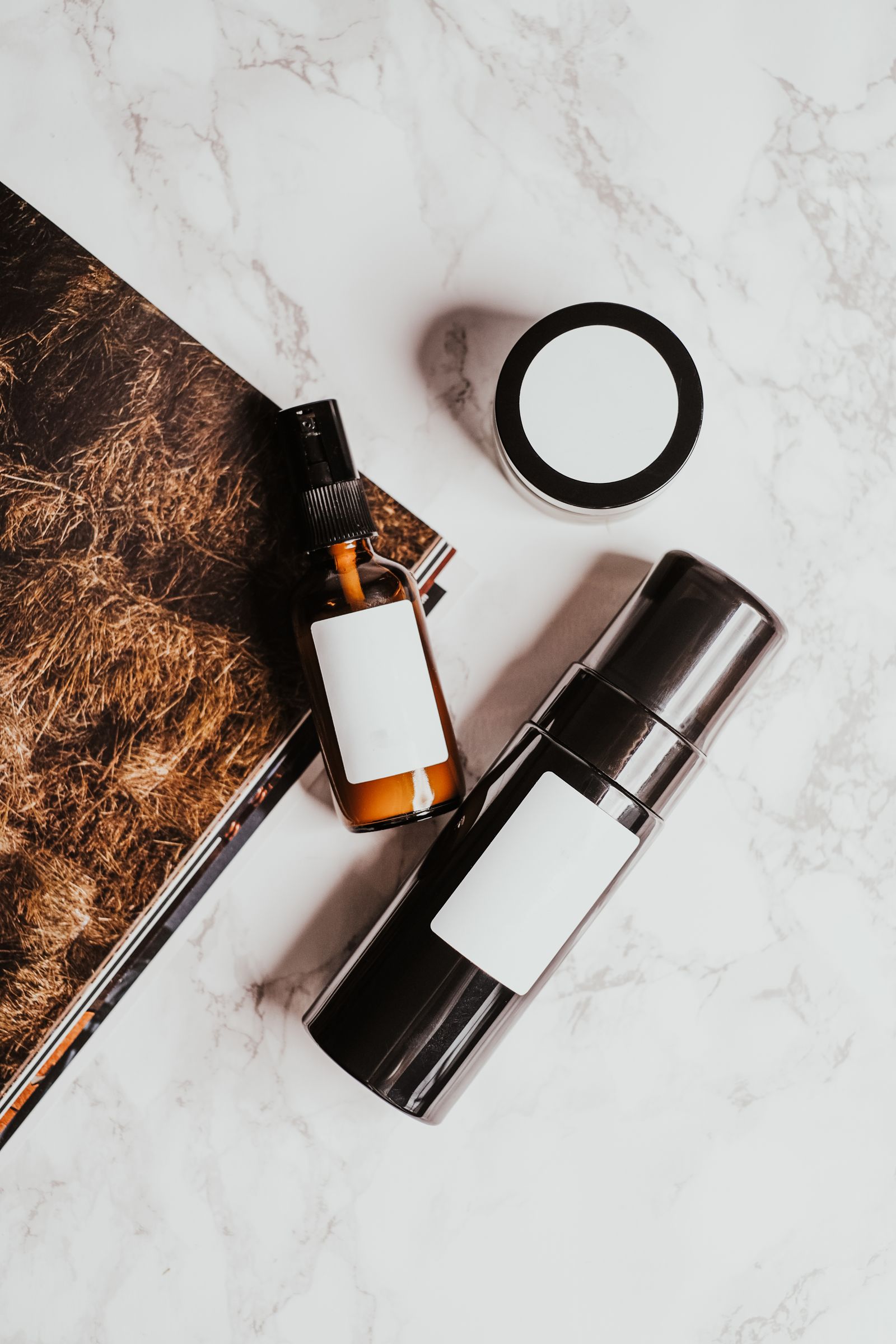 Skincare bottles and a jar arranged on a white marble surface