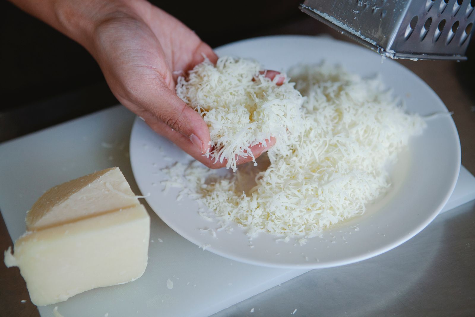 Freshly grated cheese held in a hand over a bowl
