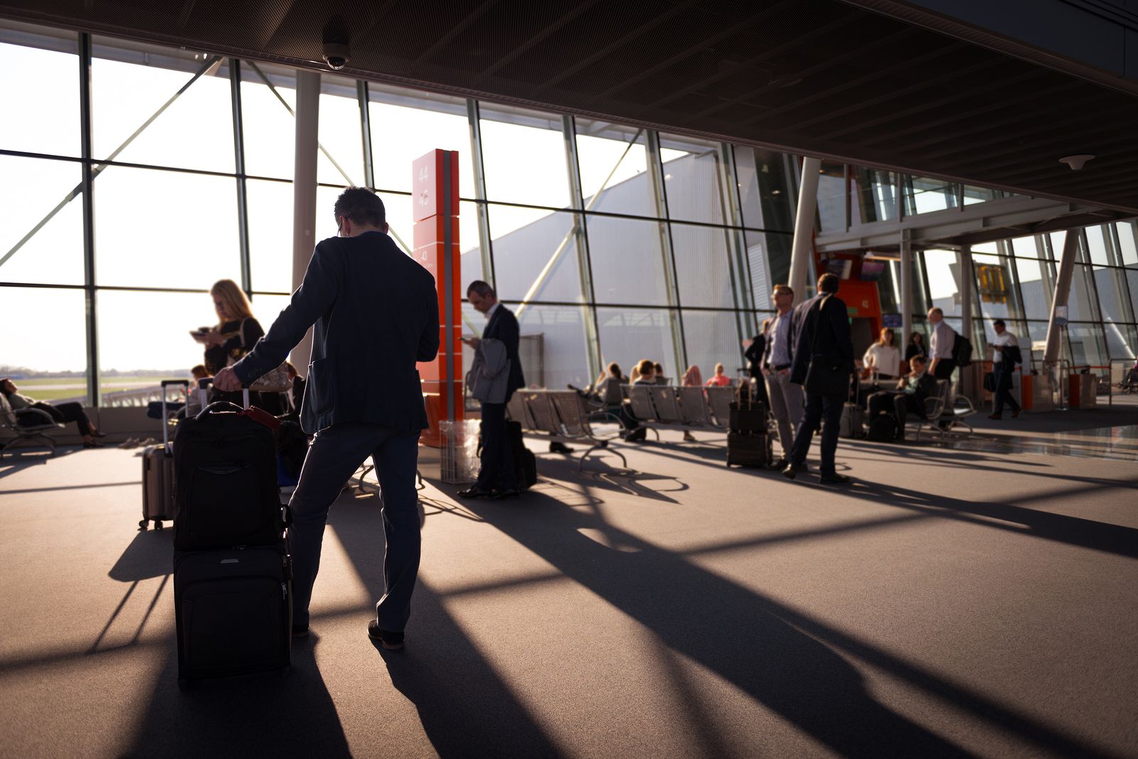 Travelers with carry-on luggage waiting in a busy airport terminal