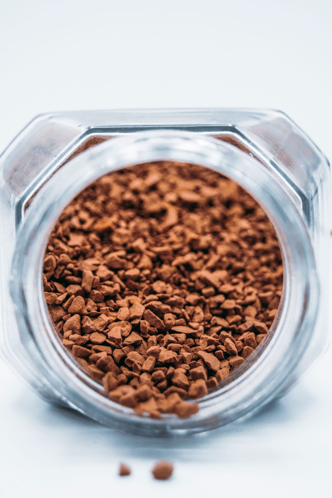 A jar of cold brew coffee steeping with grounds beside fresh beans