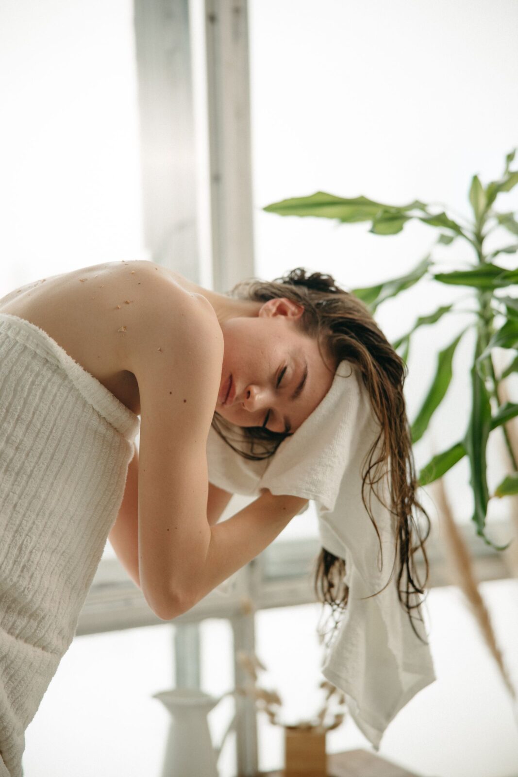 A woman blow drying her hair at home