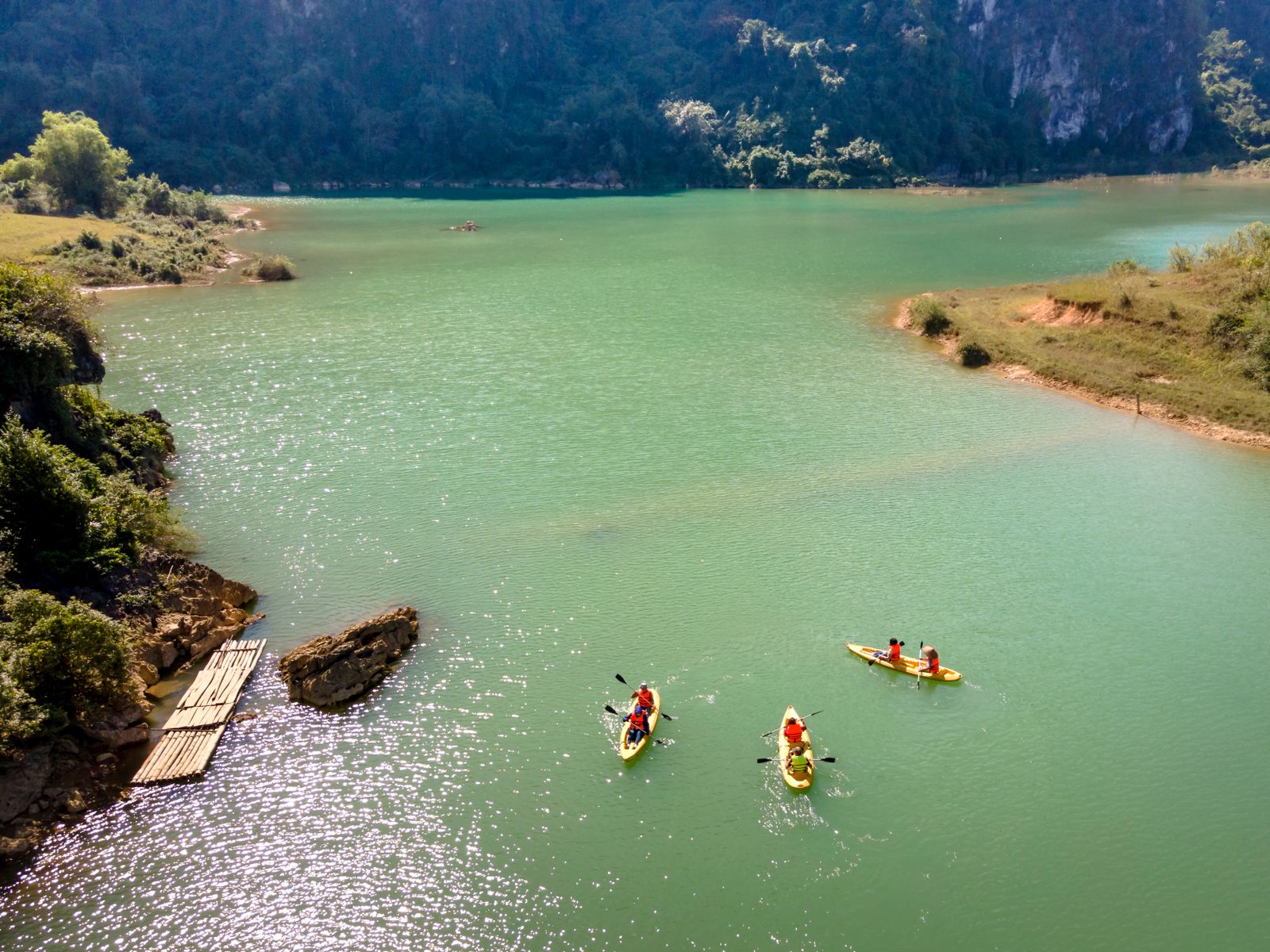 Waterproof roll-top dry bags on a kayak beside a lake