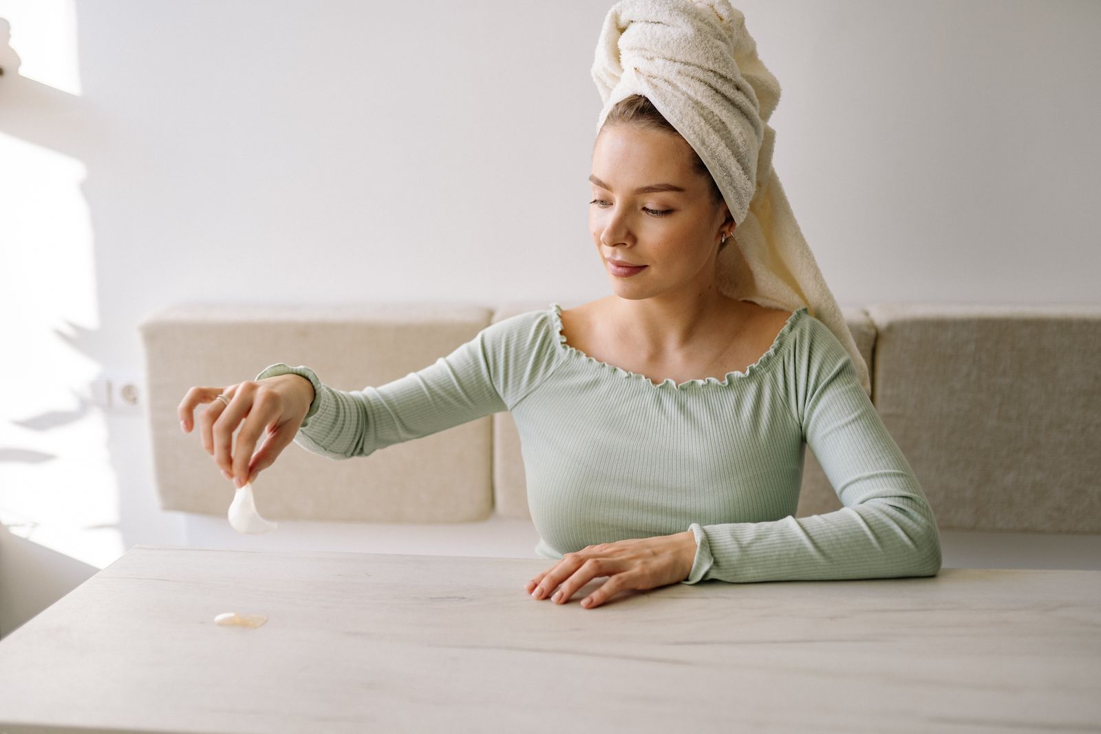 Woman with a head towel holding an under-eye patch during a skincare routine