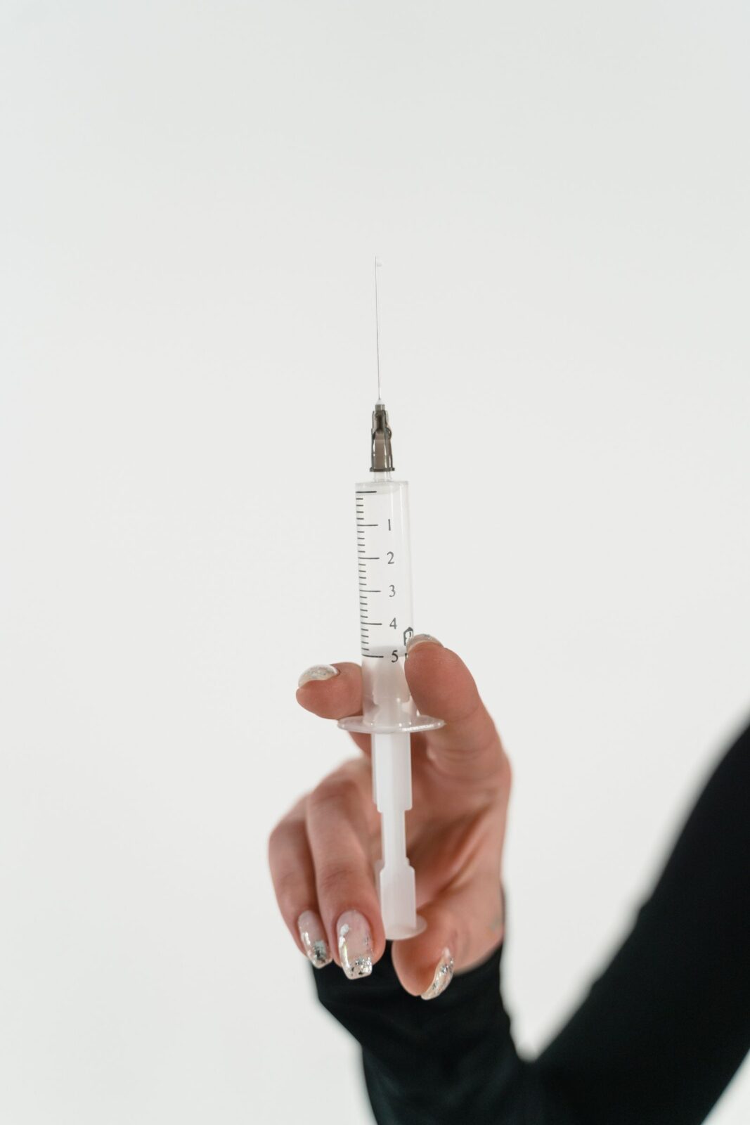 A generic injection pen beside a measuring tape on a neutral surface