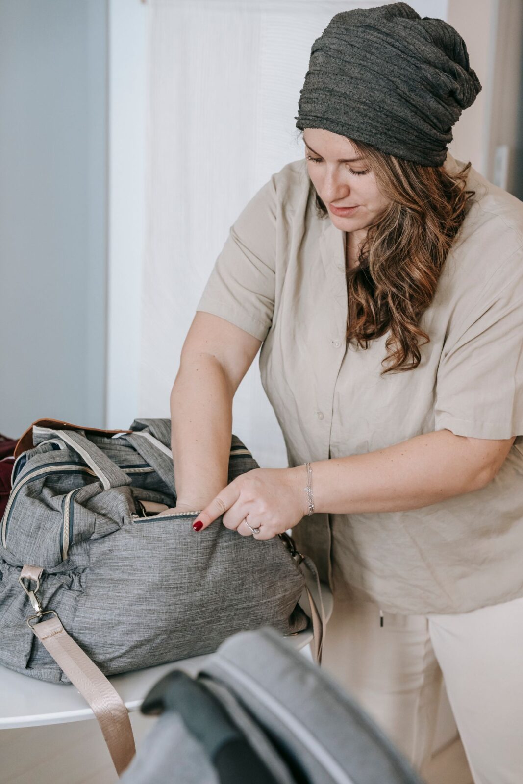 Mother packing a plain grey diaper bag at home before heading out with her baby