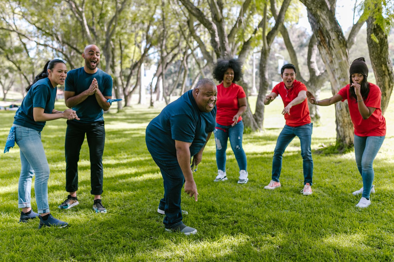 Four people playing roundnet spikeball on a lawn around a small circular net