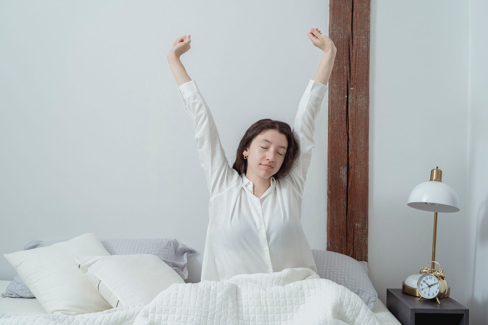 A person waking up in bed in soft morning light