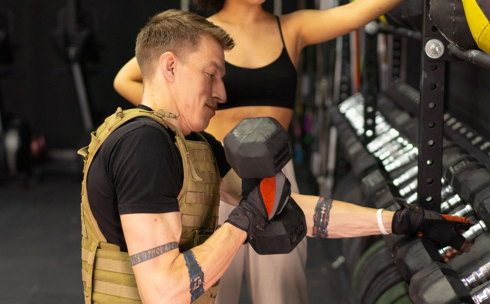 Person in a weighted vest holding a dumbbell during a workout